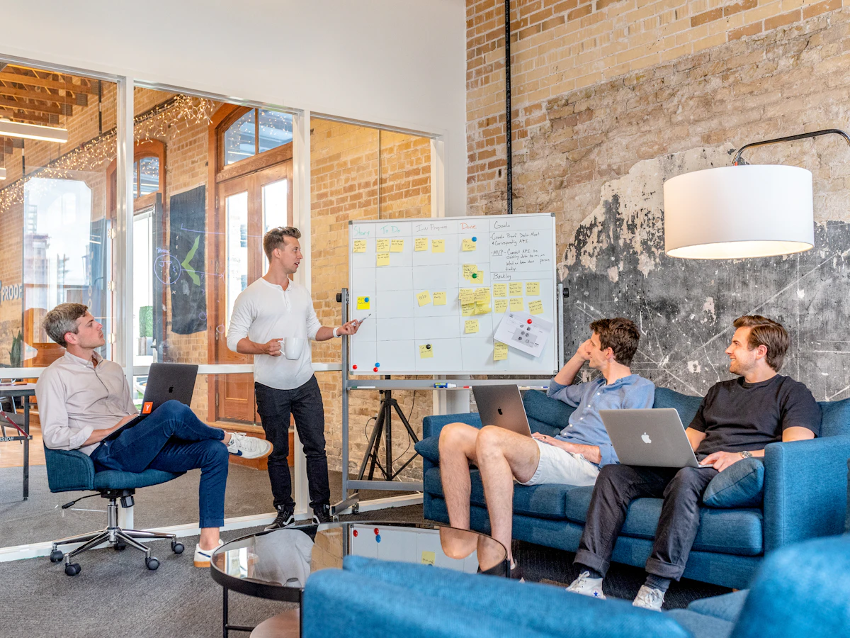 A team meeting in an open office with laptops and a whiteboard