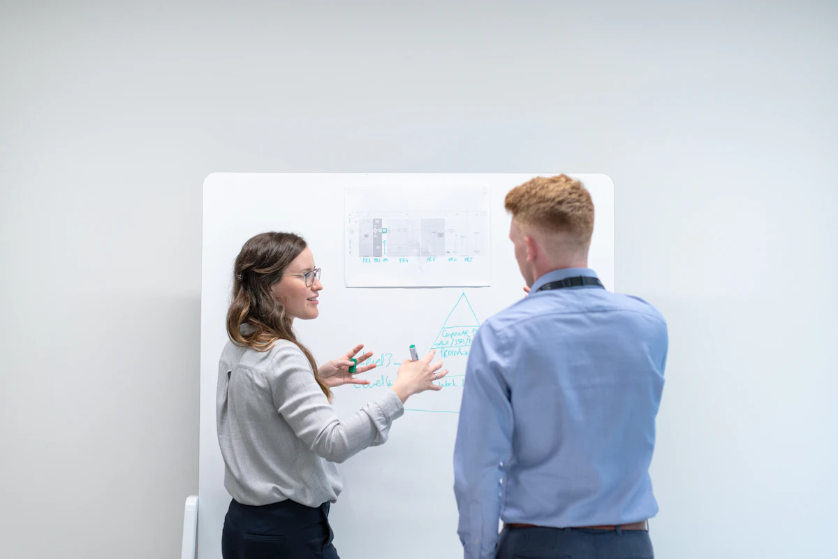 Two colleagues talking through ideas at a whiteboard